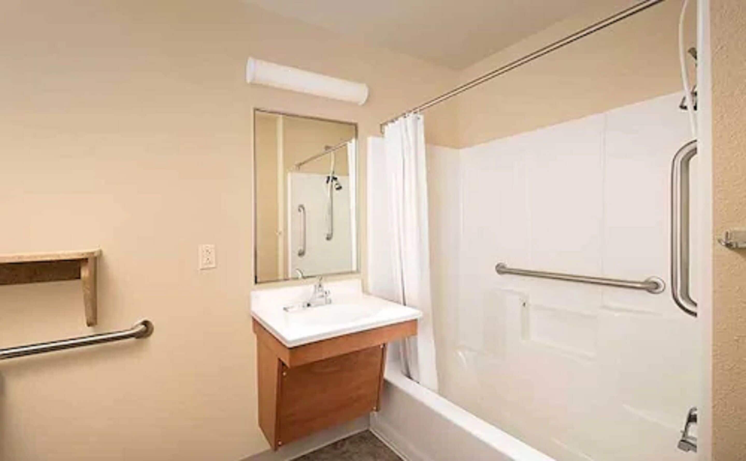 A bathroom with a shower, a sink, and a mirror.