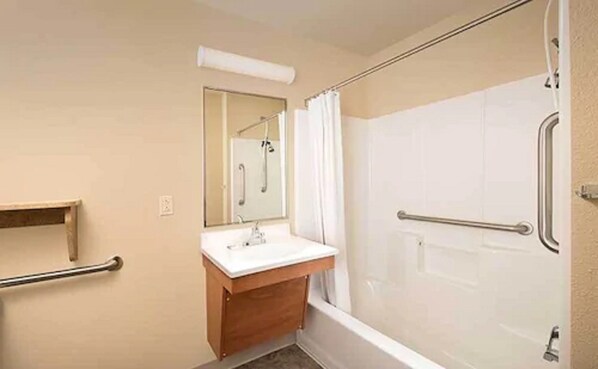 A bathroom with a shower, a sink, and a mirror.