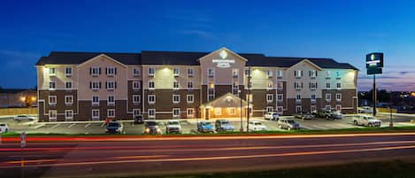 A multi-story hotel with a prominent sign, parking lot, and a well-lit entrance.