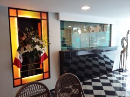 A reception area with a checkered floor, a reception desk, and a large window with a view of the outside.