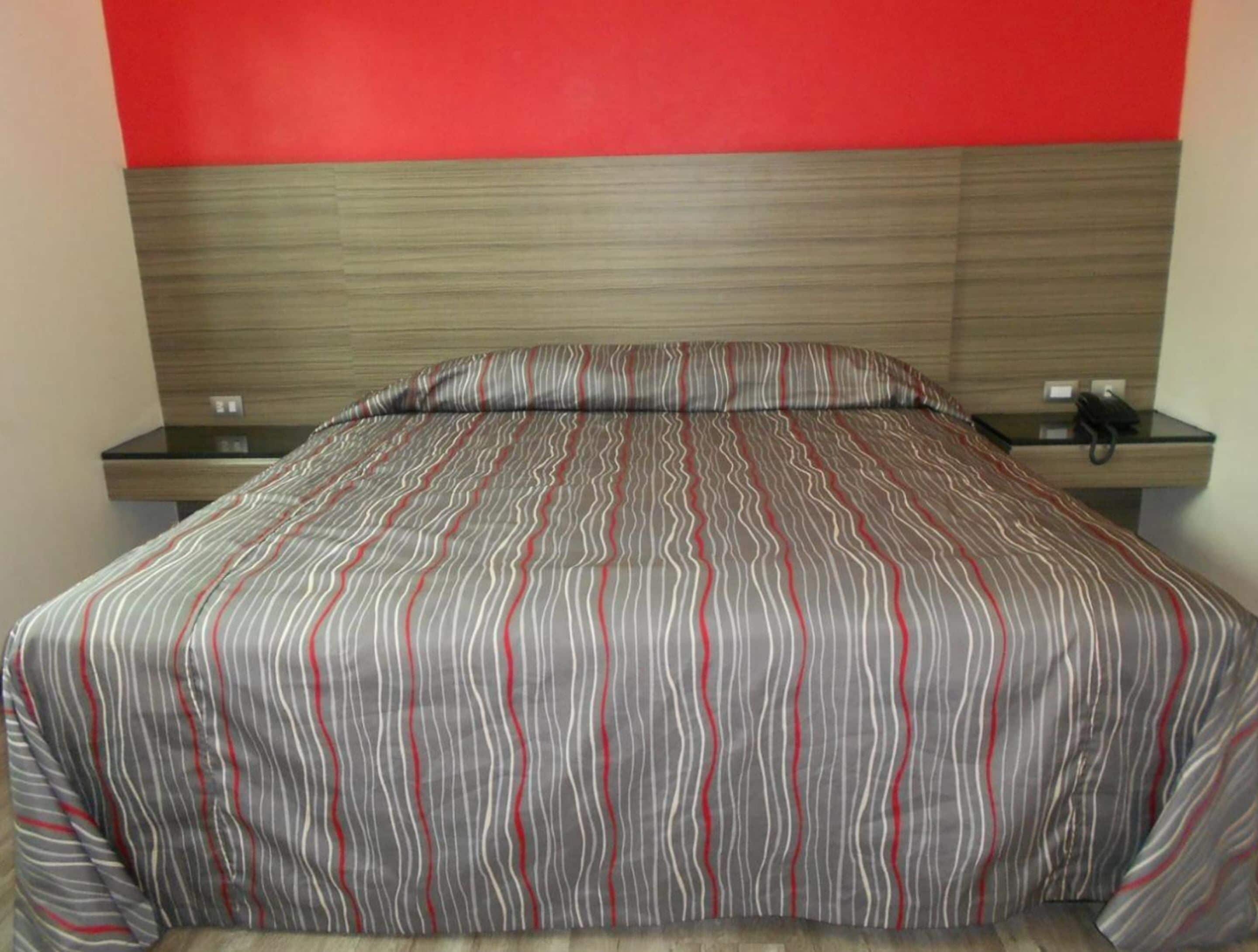 A bed with a striped bedspread, a wooden headboard, and bedside tables with lamps.