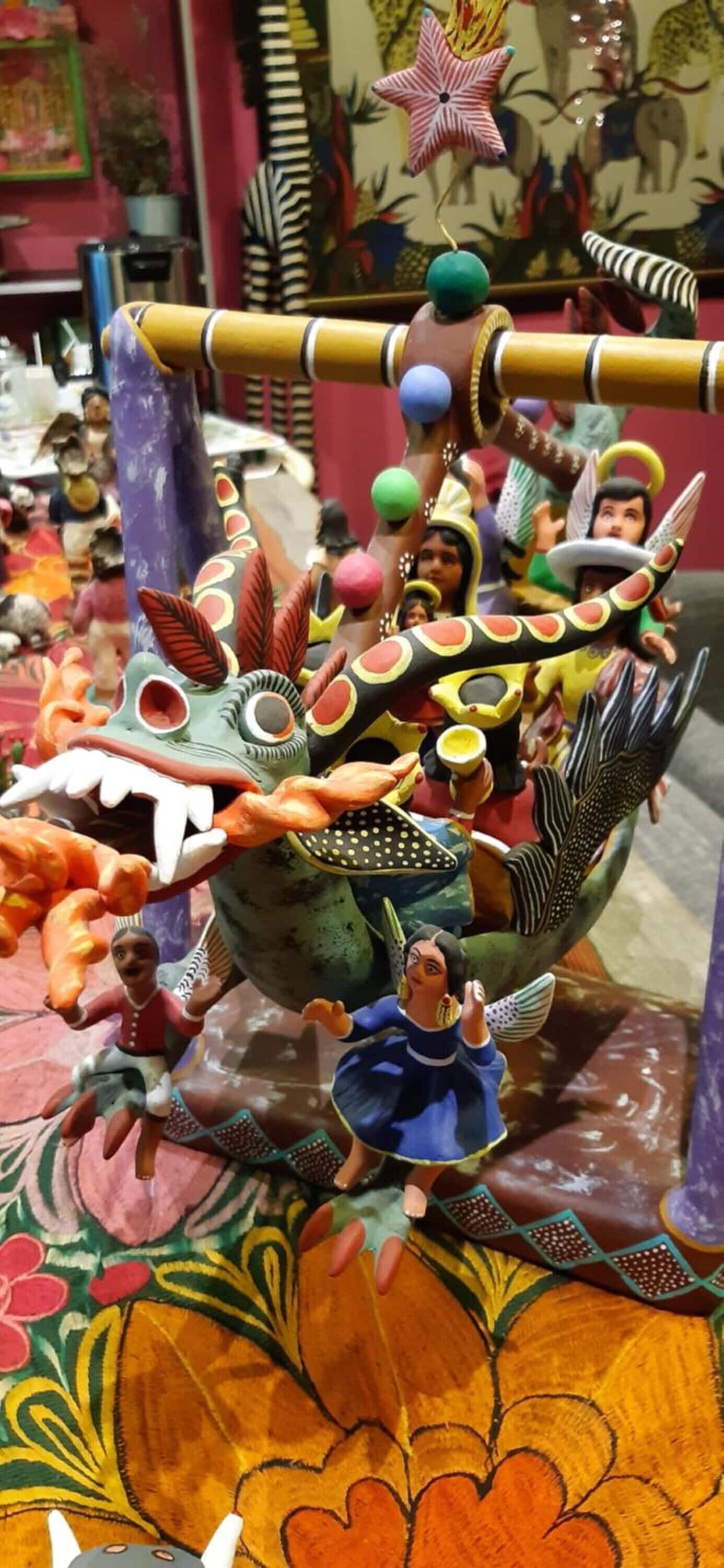 Eine farbenfrohe Drachenskulptur mit Figuren darum herum.