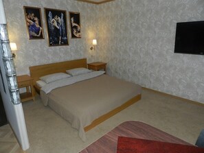 A bedroom with a large bed, two bedside tables, and three wall-mounted paintings.
