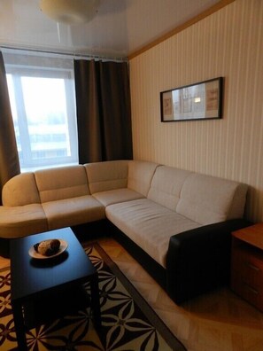 A modern living room with a sectional sofa, a small table with a plate of food, and a framed picture on the wall.