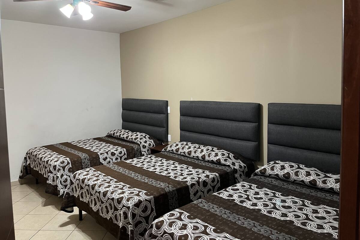A bedroom with two beds, a ceiling fan, and a tiled floor.
