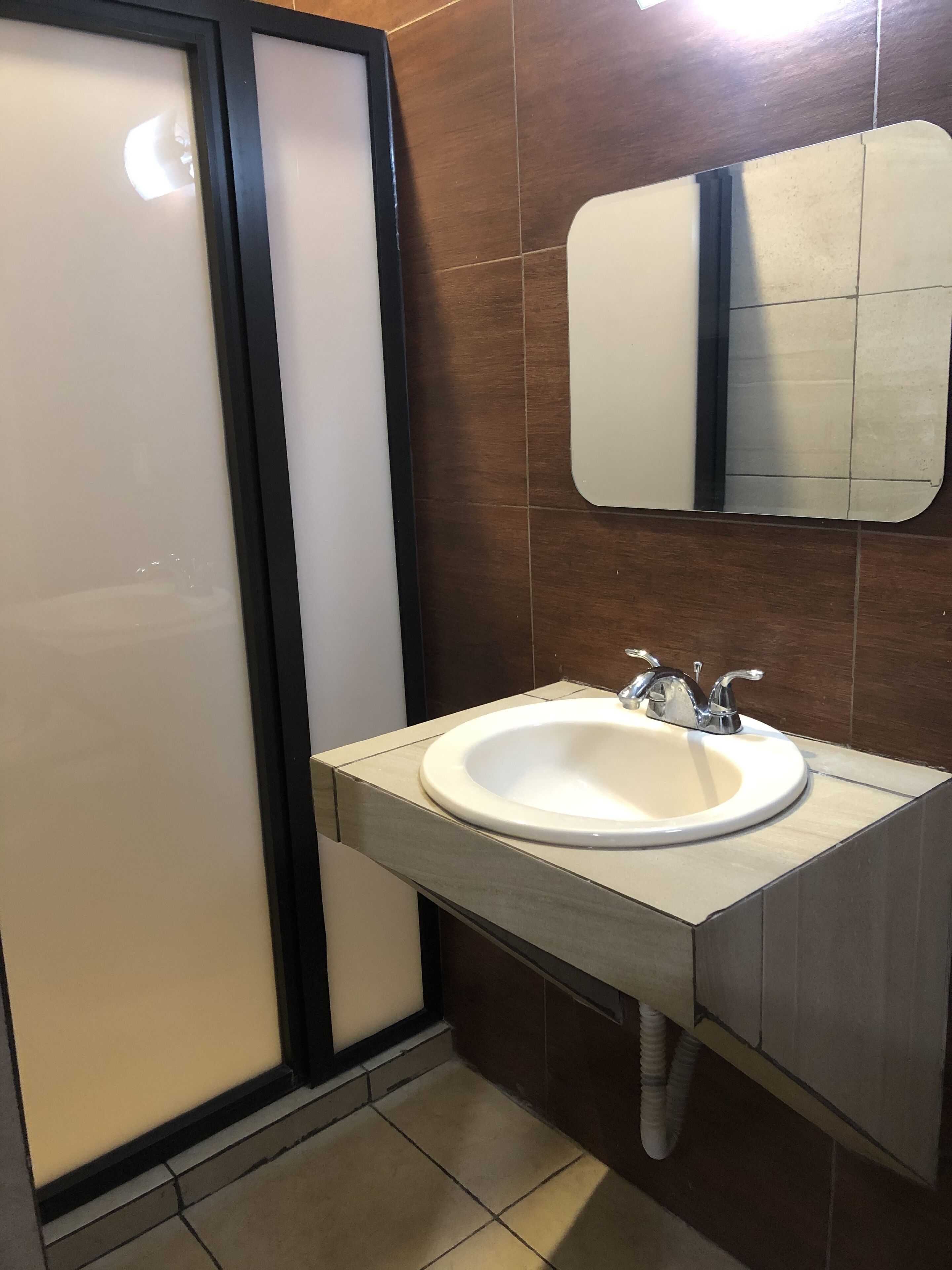 A bathroom with a white sink, a mirror, and a shower enclosure.