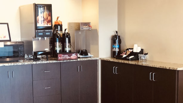 A kitchen with dark cabinets, a microwave, a coffee machine, and a coffee maker. - Budget Motel (Burley)