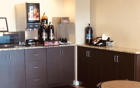 A kitchen with dark cabinets, a microwave, a coffee machine, and a coffee maker.