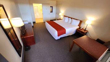 Een hotelkamer met een groot bed, twee nachtkastjes met lampen, een bureau en een stoel.