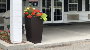 A motel with a large planter of flowers in front, a sign reading "BUDGET MOTEL", and a door with a "PULL" sign. - Budget Motel (Burley)