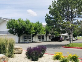 A row of single-story motel buildings with a parking area in front.
