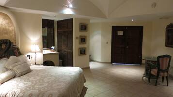 A bedroom with a bed, a desk, a chair, a wardrobe, and a door.