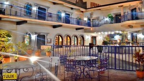 Un patio de varios niveles con mobiliario exterior, balcones y plantas en macetas.