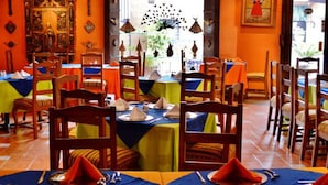 Un restaurante con mesas dispuestas para comer, sillas y una cruz en la pared.