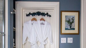 A room with a white door, a wooden side table with a basket, and a framed picture on the wall.