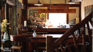 A rustic interior with wooden beams, a bar area, and a large painting on the wall.