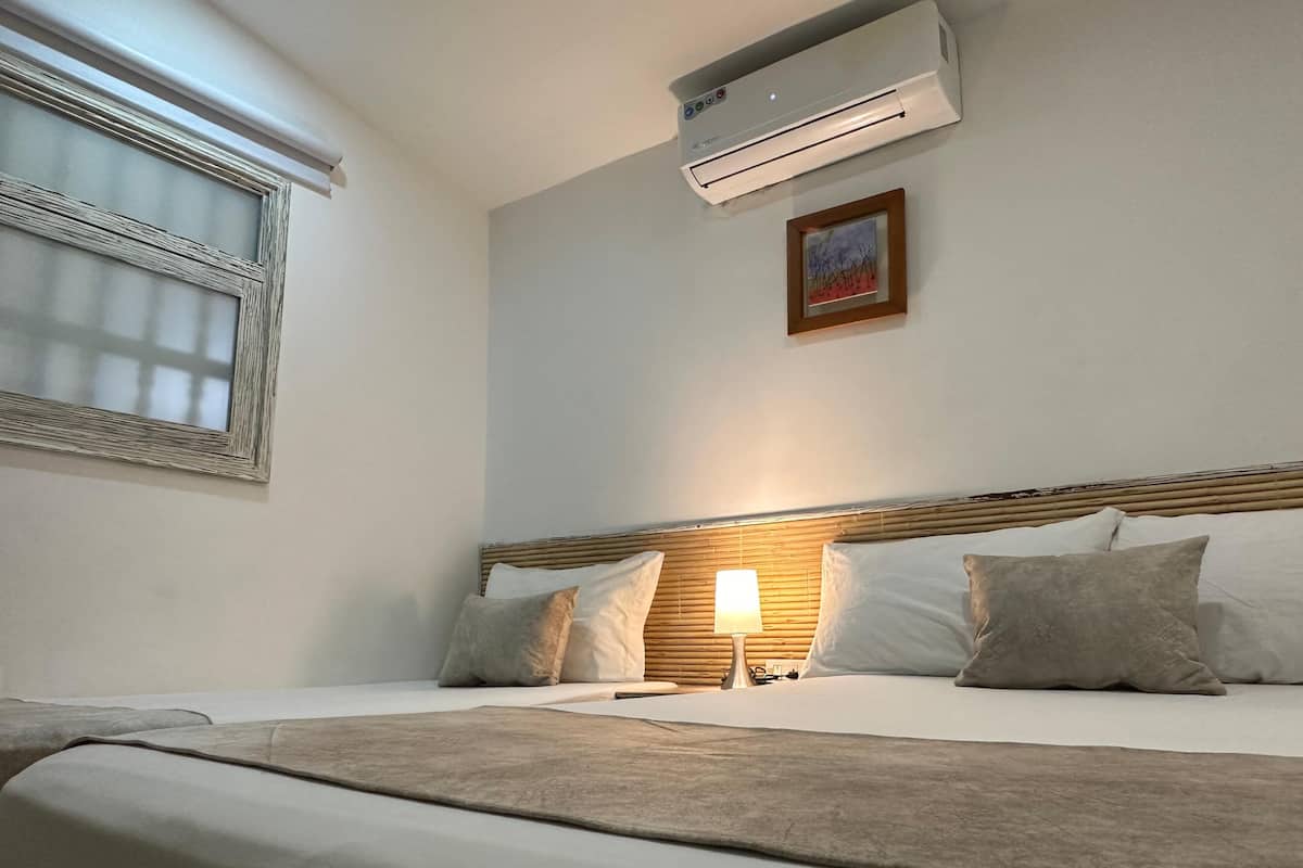 A hotel room with a bed, bedside lamp, and an air conditioner.