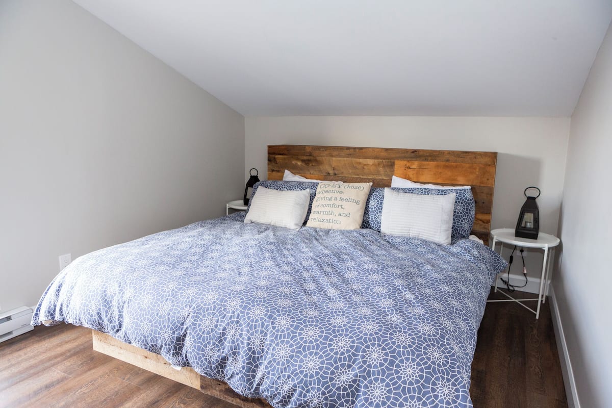 Une chambre à coucher avec une tête de lit en bois, une couvre-lit à motifs et deux tables de chevet avec des lampes.