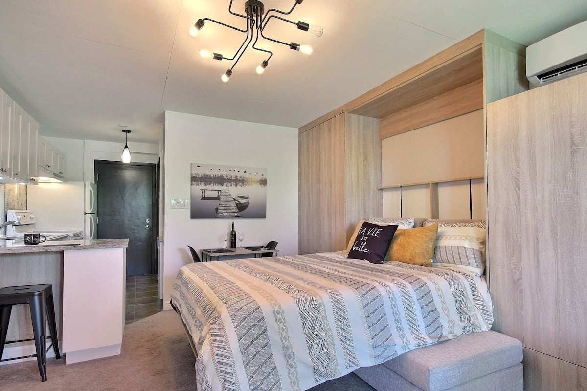 Une chambre moderne avec un grand lit, un bureau et un coin cuisine.