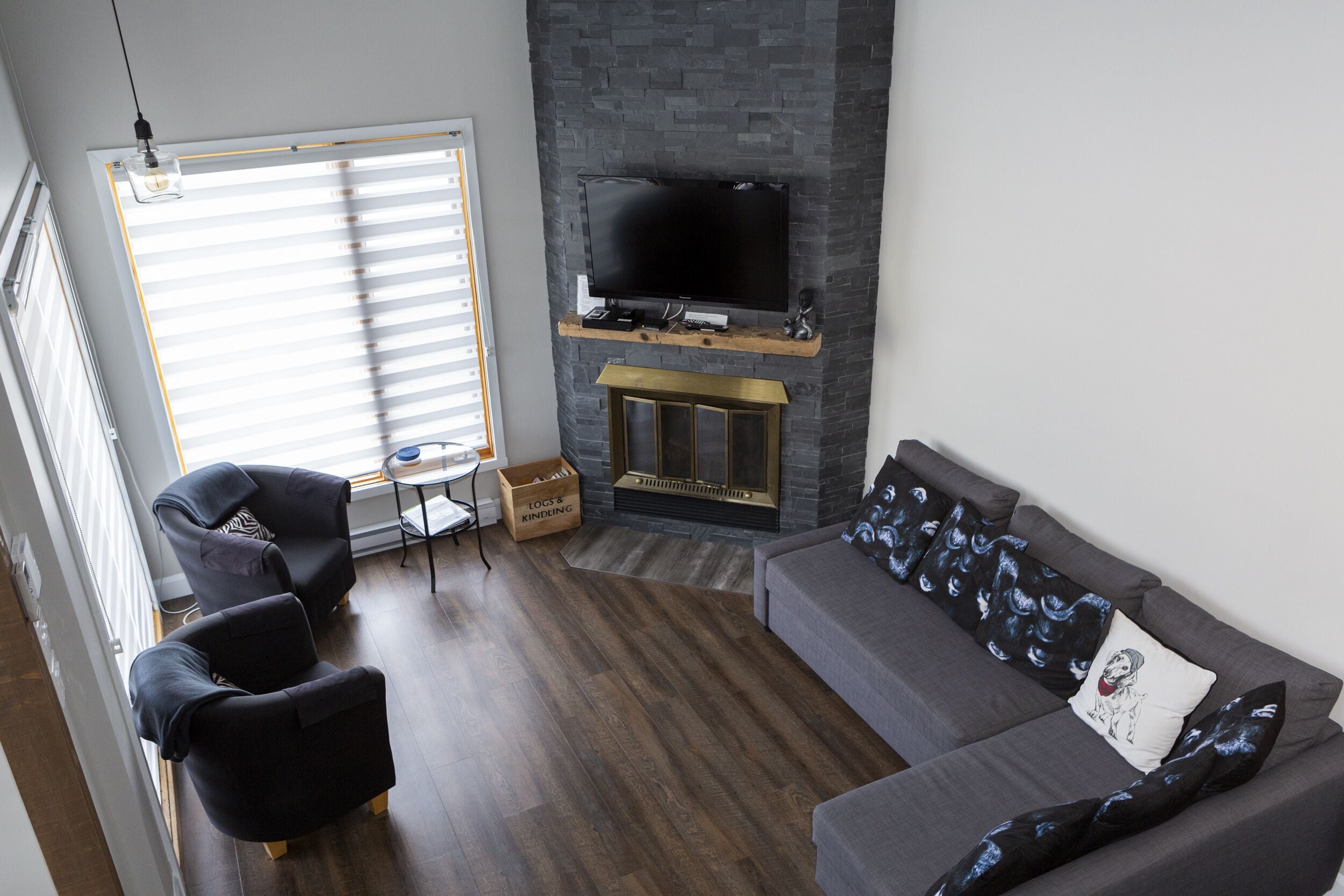 A modern living room with a fireplace, a flat-screen TV mounted above it, and a sofa with decorative pillows.