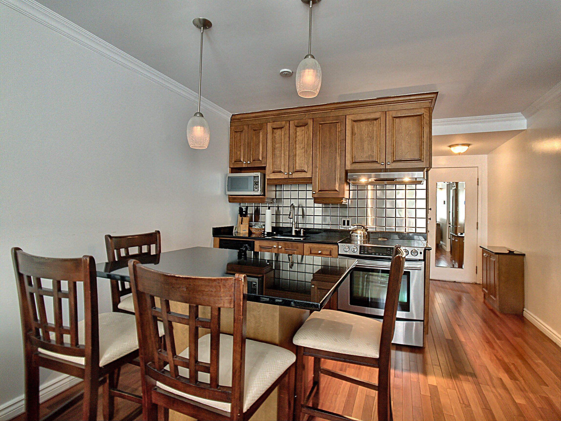A kitchen with wooden cabinets, a microwave, a stove, and a dining area with chairs.