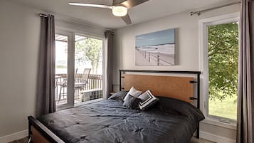 A bedroom with a bed, a ceiling fan, a window with curtains, and a view of the outdoors.