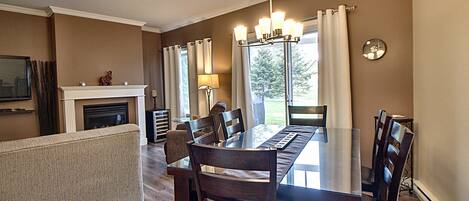 Un comedor con mesa y sillas de madera, chimenea y vistas al exterior.
