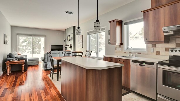 A modern kitchen with a central island, stainless steel appliances, and wooden cabinetry. - Condo 2 Bedrooms Jardin des Sables (Orford)