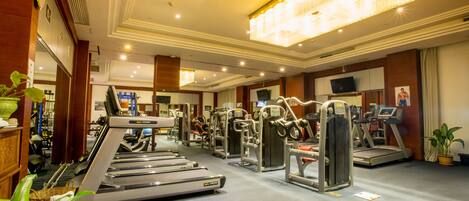 Un gimnasio con cintas de correr, elípticas y equipo de pesas.