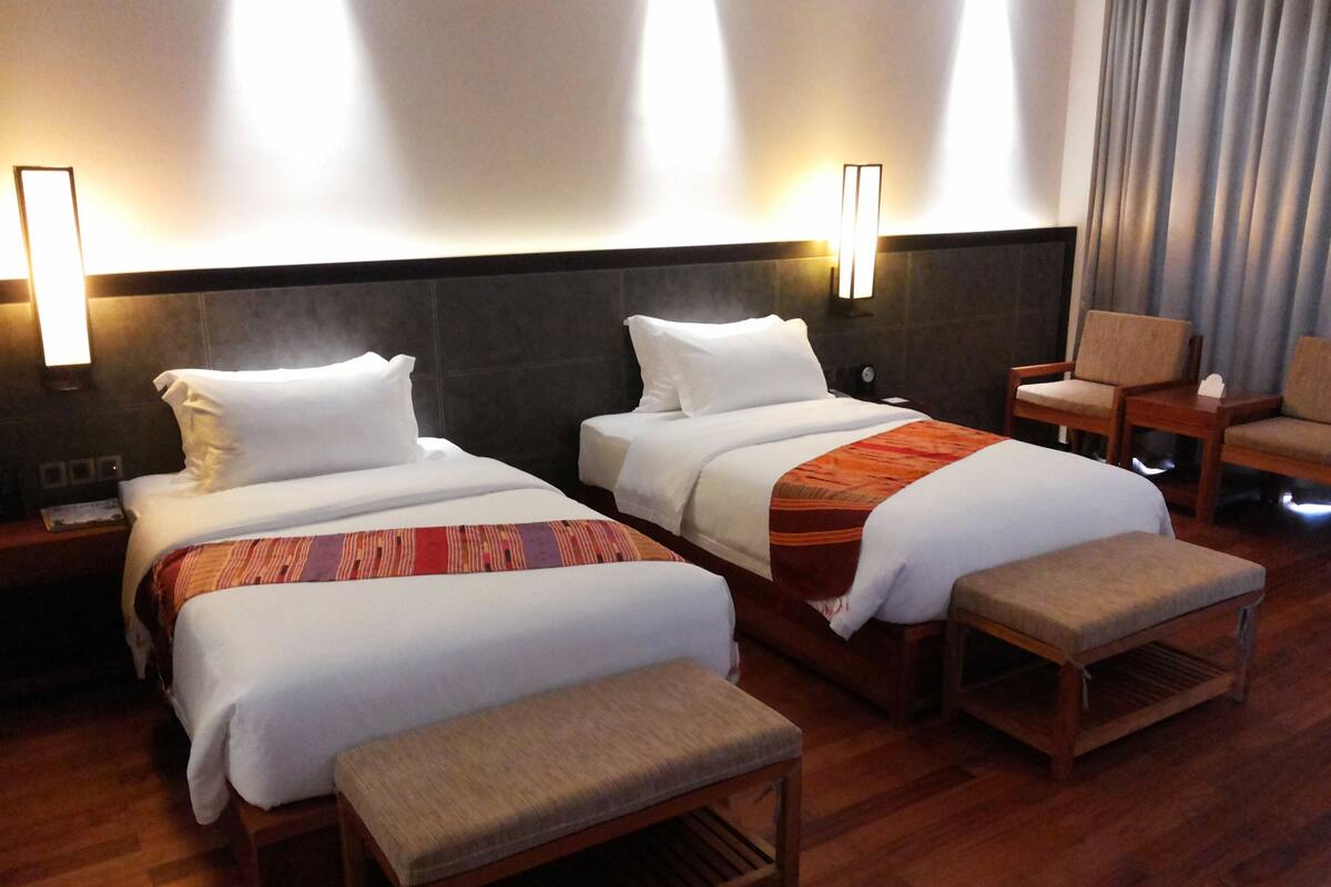Ein Hotelzimmer mit zwei Betten, einer Bank und einem Sessel.