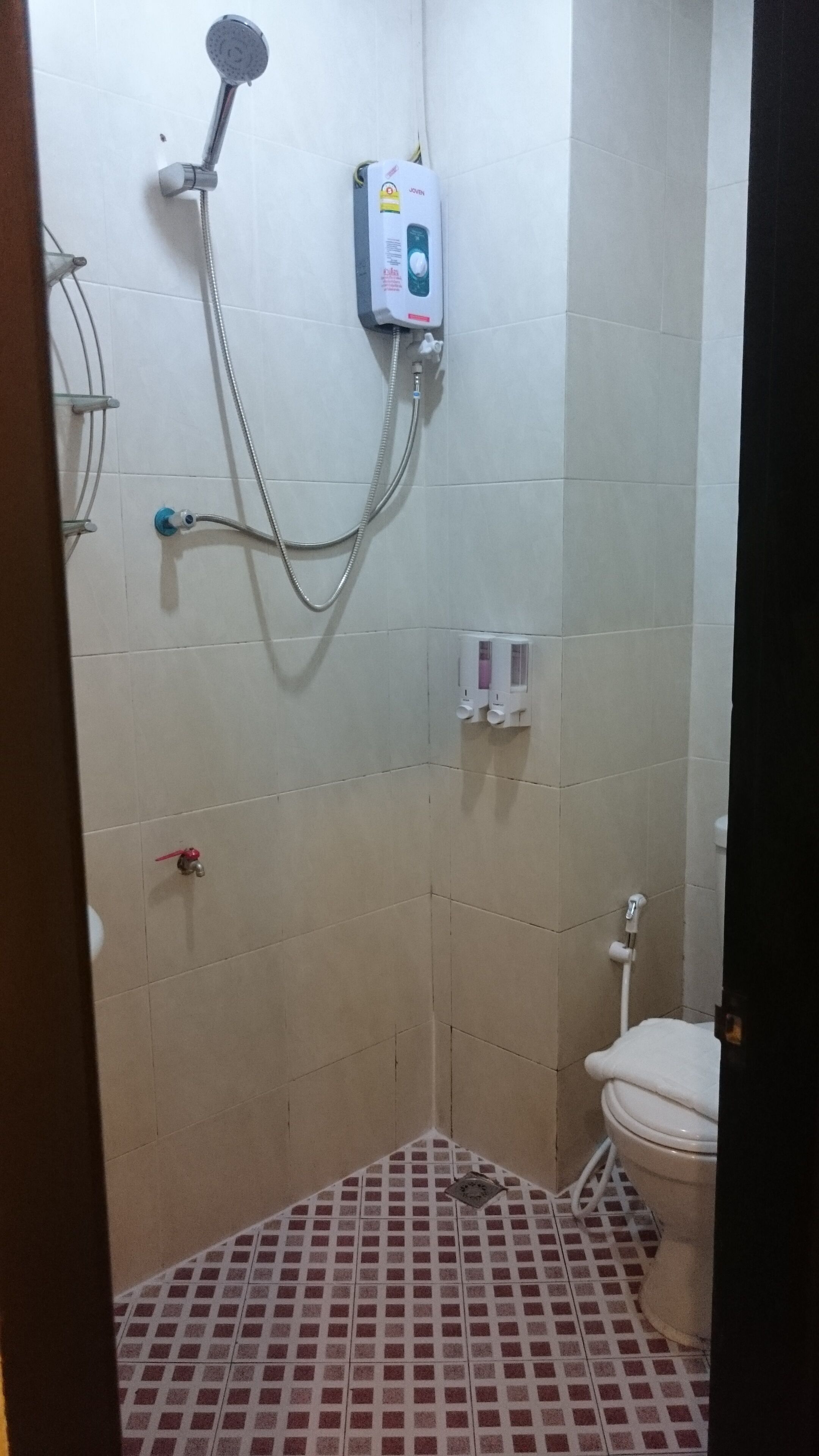 A small bathroom with a shower, toilet, and a tiled floor.