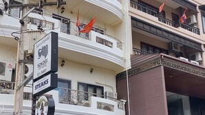 Un immeuble à plusieurs étages doté de balcons, une enseigne indiquant « Sokdee City Hotel » et un présentoir affichant le menu du restaurant, le tout situé à l’extérieur.