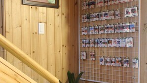 Ein Holzinnenraum mit einer Treppe, einem Korkbrett mit Postkarten und einer Topfpflanze.