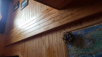 Un interior de madera con techo inclinado, un mapa en la pared y una decoración con corona de laurel.