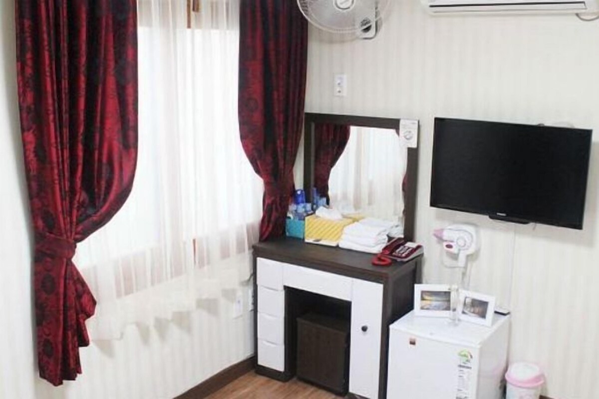 Une chambre d’hôtel équipée d’un bureau, d’un miroir, d’une télévision et d’une petite armoire.