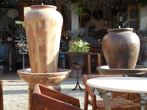 A rustic outdoor seating area with large ceramic planters, wooden furniture, and various decorative items.