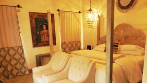 A hotel room with a large bed, a smaller bed, a sofa, and a painting on the wall.