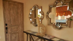 A wooden door, a console table with a sculpture, and two mirrors on the wall.