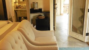 A room with a white upholstered sofa, a small table with a basket, and a door leading to a balcony.