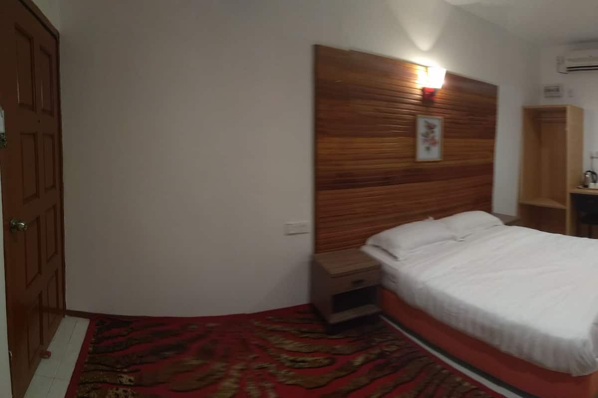 Un dormitorio con cabecera de madera, cama individual, mesita de noche, pequeño armario de madera y alfombra roja con diseño.