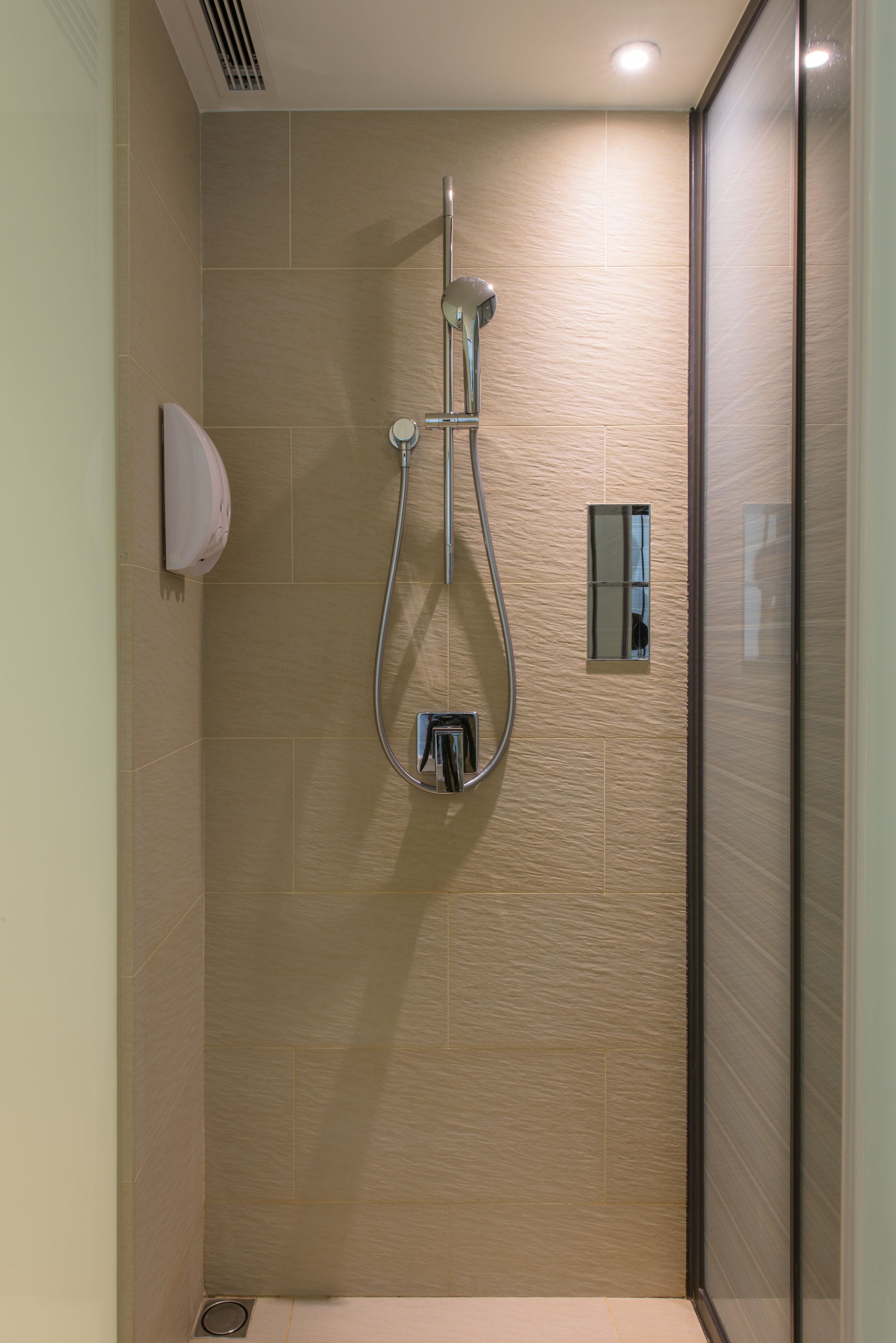 A modern shower with a handheld showerhead and a wall-mounted faucet.