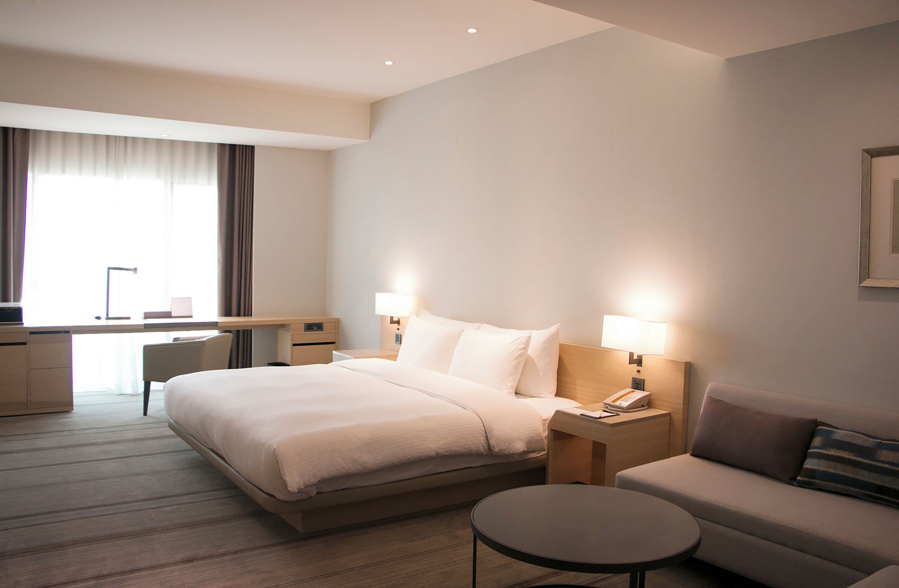 Une chambre d’hôtel avec un grand lit, des tables de chevet avec des lampes, un canapé, un bureau et une chaise.