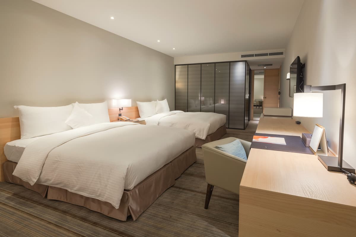 Une chambre d’hôtel avec un grand lit, des tables de chevet, un bureau et une armoire.