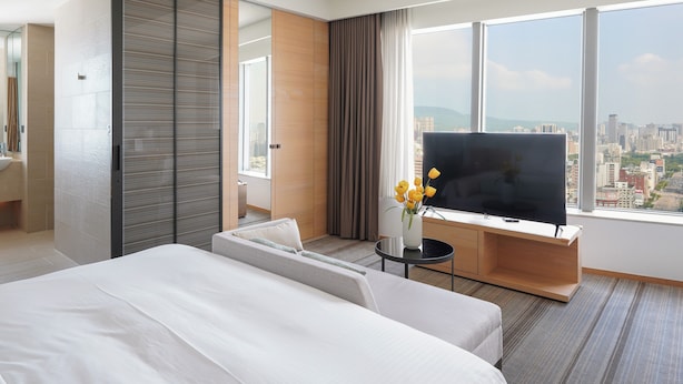 A modern hotel room with a large bed, a TV, and a city view. - HOTEL COZZI Zhongshan Kaohsiung (Kaohsiung)