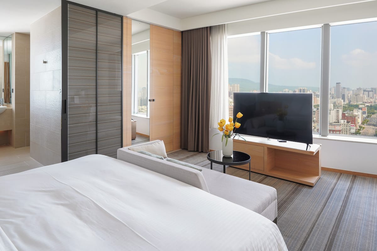 Une chambre d’hôtel moderne avec un grand lit, une télévision et une vue sur la ville.