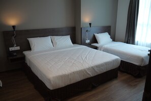 A hotel room with two beds, wooden flooring, and bedside lamps.