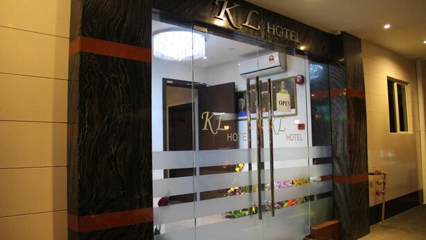 A hotel entrance with a glass facade, a sign reading "KC Hotel", and a "OPEN" sign above the door. - KL Hotel (Labuan)