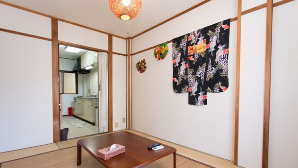 Una habitación tradicional japonesa con suelo de tatami, una mesa de madera y un fusuma decorado con motivos florales.