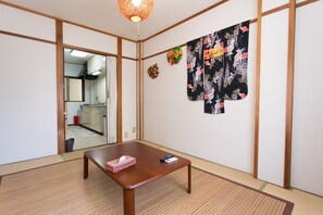A traditional Japanese room with tatami flooring, a wooden table, and a shoji screen with floral patterns. - Iyashi Space MANA (Kyoto)