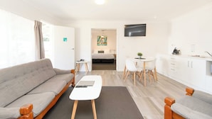 Una habitación moderna y bien iluminada con sofá, una mesita, comedor y cocina.